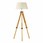 Wooden tripod floor lamp with a beige lampshade on a white background