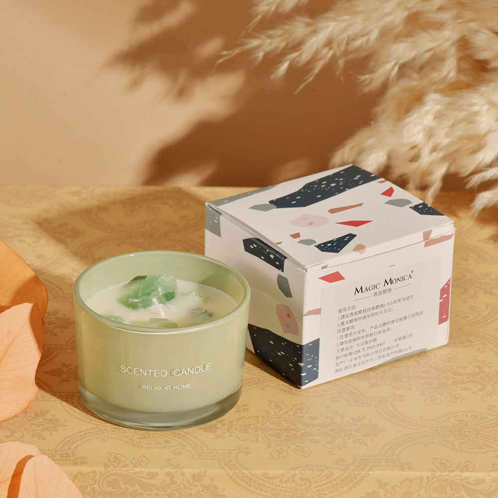 Green scented candle with decorative box on a wooden surface